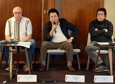 Luis Villanueva sentado entre dos expositores en la ICM