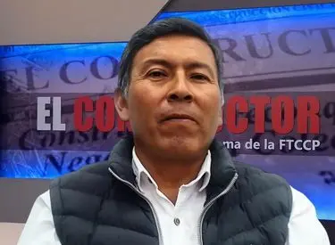 Lugue Espinoza con camisa celeste y chaleco azul con fondo del estudio de Tv de El Constructor